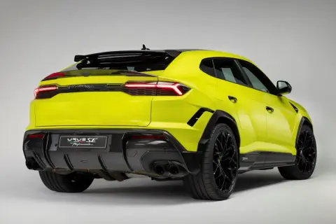 Jaskrawożółty Lambo Urus z czarnymi detalami i felgami, prezentujący sportowy tył z dyfuzorem i podwójnymi końcówkami wydechu.