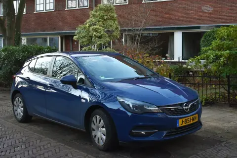 Niebieski Opel Astra K 1.6 CDTI zaparkowany przed domem z cegły.