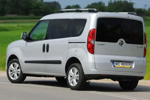 Srebrny Opel Combo C w ruchu, z tyłu widoczny bagażnik dachowy i przyciemniane szyby.