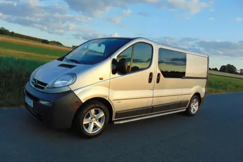 Srebrny Opel Vivaro 2.5 CDTI na drodze, zachód słońca. Wiele osób szuka opinii na forum o tym modelu.