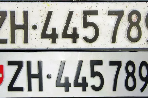 Dwie tablice rejestracyjne z numerem ZH 445789. Górna jest starsza, dolna ma herb Szwajcarii i kantonu Zurych.