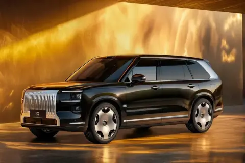 Elegancki, ciemny SUV Zeekr 9X z chromowanym grillem i futurystycznymi felgami, prezentowany w złotym, oświetlonym wnętrzu.