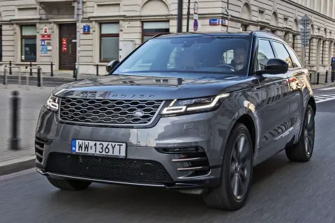 Szary Range Rover Velar jedzie ulicą miasta. Kierowca wpatruje się w drogę.