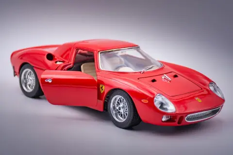 Czerwone Ferrari 250 GTO z otwartymi drzwiami, model kolekcjonerski, błyszczące felgi i detale.