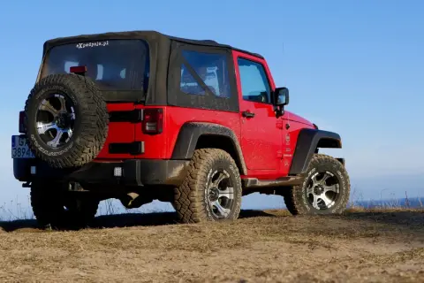 Czerwony Jeep Wrangler, gotowy na każdą wyprawę, niczym przekraczający Rubikon.