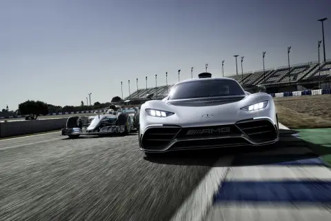 Wyścigowy bolid F1 i biały Mercedes-AMG Project One pędzą po torze.