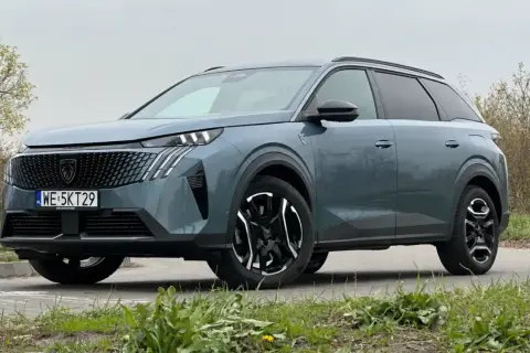 Nowy Peugeot 5008 w kolorze szarym, z czarnymi felgami i nowoczesnym grillem. Wiele osób szuka peugeot 5008 opinie przed zakupem.