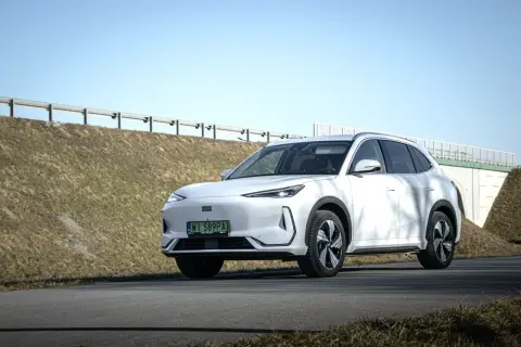 Biały Geely EX5 na tle nieba i nasypu drogowego. Elegancki SUV gotowy na podróż.