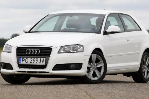 Białe Audi A3 2004 na drodze, z widocznym grillem i tablicą rejestracyjną PO 299 JA.