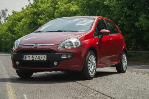 Czerwony Fiat Grande Punto na tle zieleni.