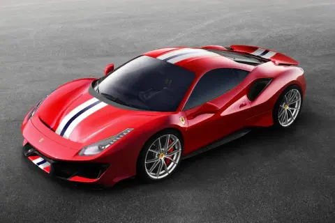Czerwone Ferrari Pista z białymi i niebieskimi pasami na masce i dachu, zaparkowane na szarym asfalcie.