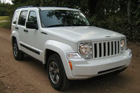 Biały Jeep Liberty 3.7 na drodze leśnej. Wiele osób szuka jeep liberty 3.7 opinie przed zakupem.