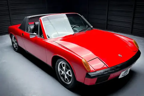 Czerwony Porsche 914 z czarnym dachem targa, gotowy do jazdy po krętych drogach.