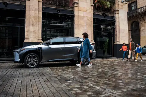 Rodzina idzie obok ładowanego elektrycznego SUV-a Toyoty. EV mode Toyota co to? To przyszłość motoryzacji.