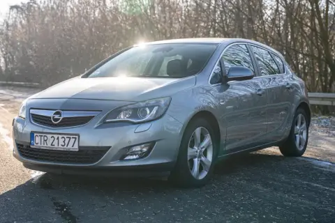 Szary Opel Astra J 1.7 CDTI na tle drzew w zimowym słońcu.