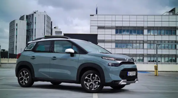 Szary Citroen C3 na parkingu przed nowoczesnymi budynkami. Wiele osób szuka **citroen c3 opinie** przed zakupem.