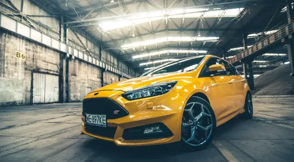 Żółty Ford Focus ST 2010 w hangarze, gotowy do akcji.