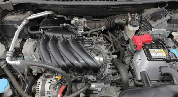 Silnik Nissan Qashqai J10, z widocznym kolektorem dolotowym, akumulatorem i innymi elementami.