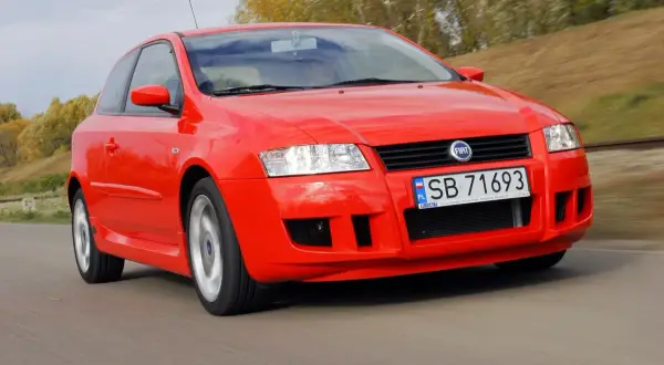 Czerwony Fiat Stilo 1.9 JTD w ruchu, z widocznym zderzakiem i tablicą rejestracyjną SB 71693.
