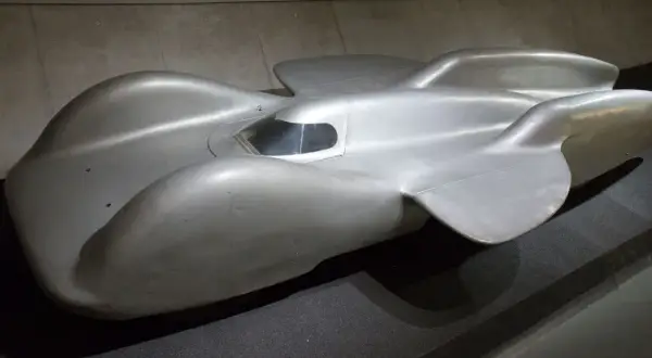 Srebrny, opływowy Mercedes T80, legendarny samochód wyścigowy, prezentuje swoje aerodynamiczne kształty.