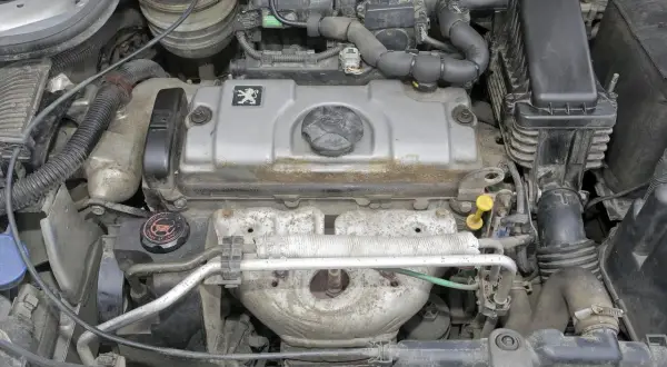 Silnik Peugeot 206 1.4 benzyna, widok z góry. Widać pokrywę zaworów z logo marki, elementy układu dolotowego i wydechowego.