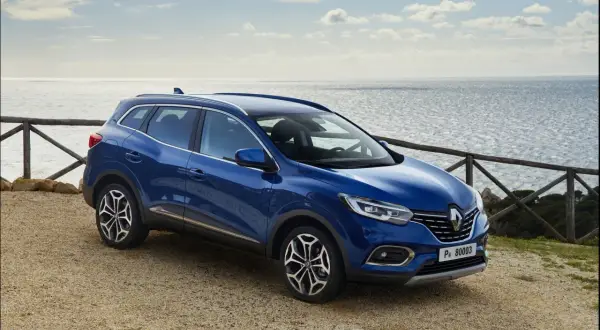 Niebieski Renault Kadjar na tle morza. Wiele pozytywnych **renault kadjar opinie** potwierdza jego wszechstronność.
