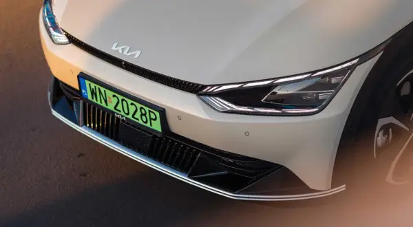 Nowy Kia z zieloną tablicą rejestracyjną WN 2028P. Zbliżenie na przednią część samochodu elektrycznego.