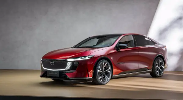 Elegancka, czerwona Mazda 6e prezentuje się na drewnianej scenie.