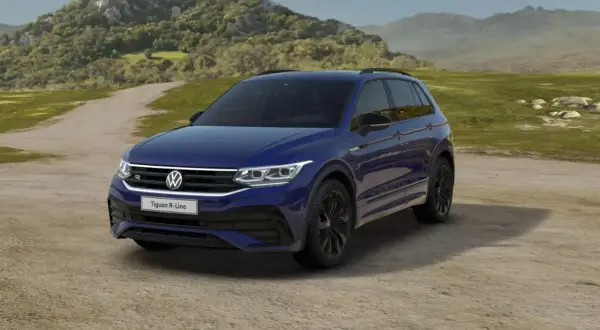 Niebieski Volkswagen Tiguan R-Line na tle krajobrazu. Wiele osób szuka volkswagen tiguan opinie przed zakupem.