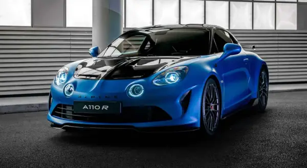 Niebieski Alpine A110 R z czarną maską i dachem, gotowy do jazdy po torze.