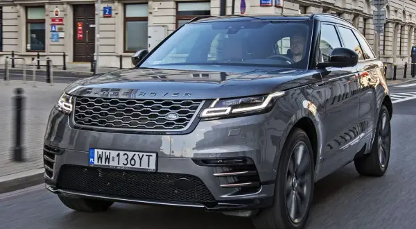 Szary Range Rover Velar jedzie ulicą miasta. Kierowca wpatruje się w drogę.