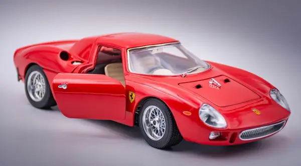Czerwone Ferrari 250 GTO z otwartymi drzwiami, model kolekcjonerski, błyszczące felgi i detale.