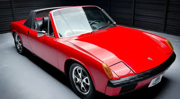 Czerwony Porsche 914 z czarnym dachem targa, gotowy do jazdy po krętych drogach.
