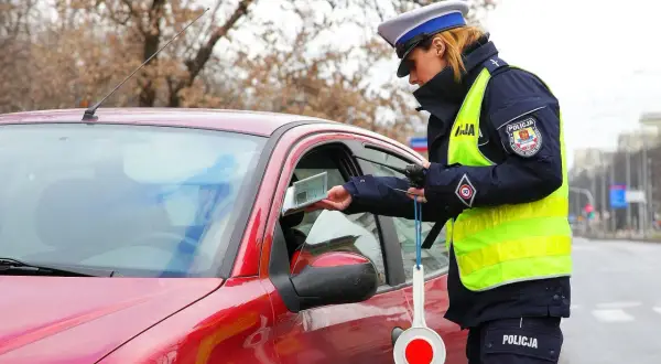 Policjantka kontroluje dokumenty kierowcy. Czy trzeba mieć przy sobie dowód rejestracyjny? Tak, w Polsce jest to obowiązkowe.