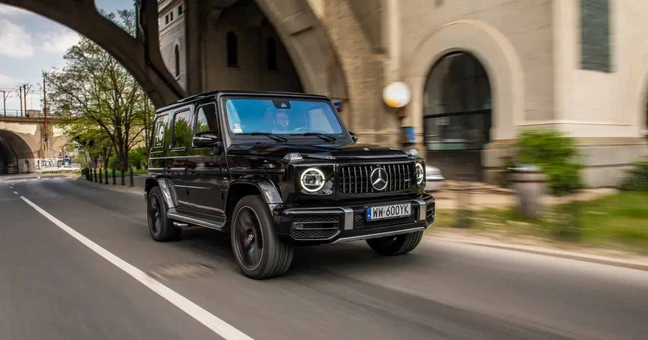 Czarny Mercedes G63 z okrągłymi światłami LED pędzi pod wiaduktem.