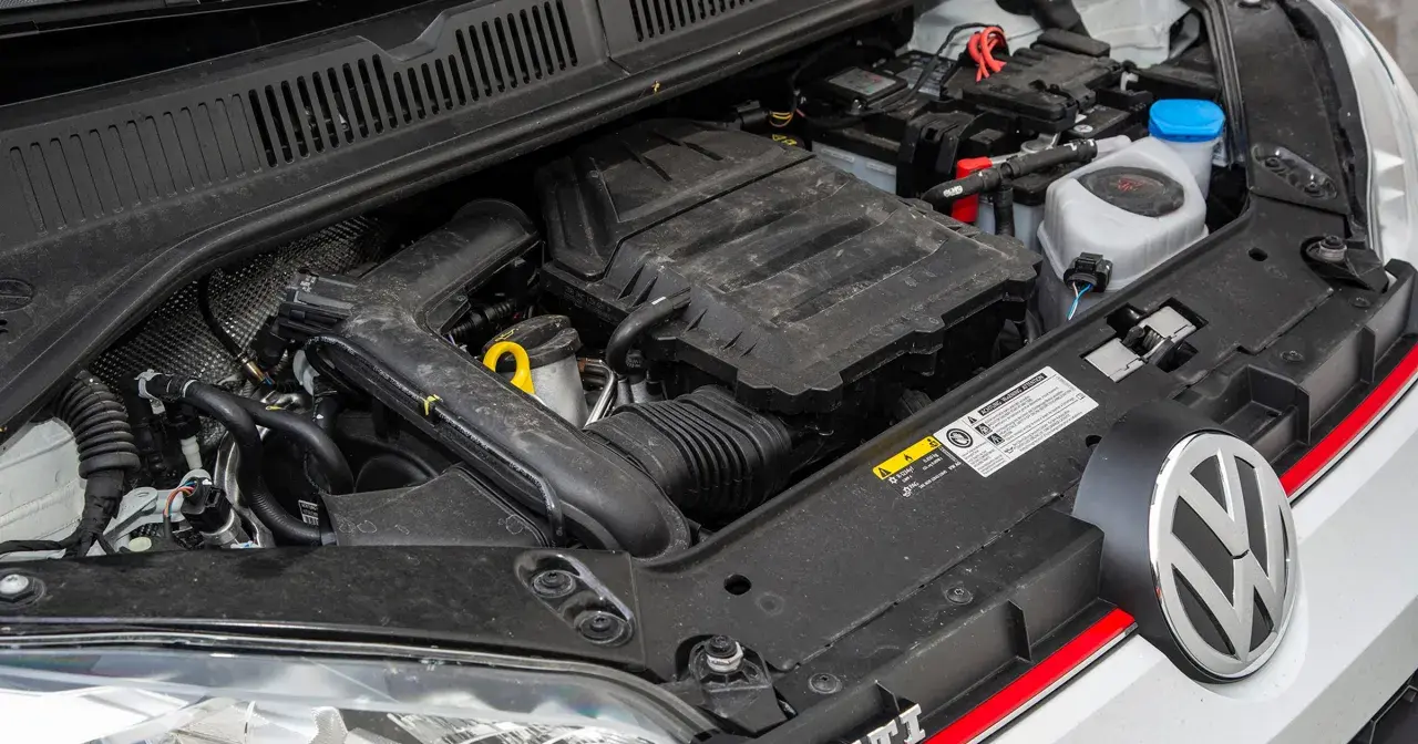 Silnik 1.0 TSI 110 KM w samochodzie Volkswagen. Widoczny akumulator, przewody i elementy osłony silnika.