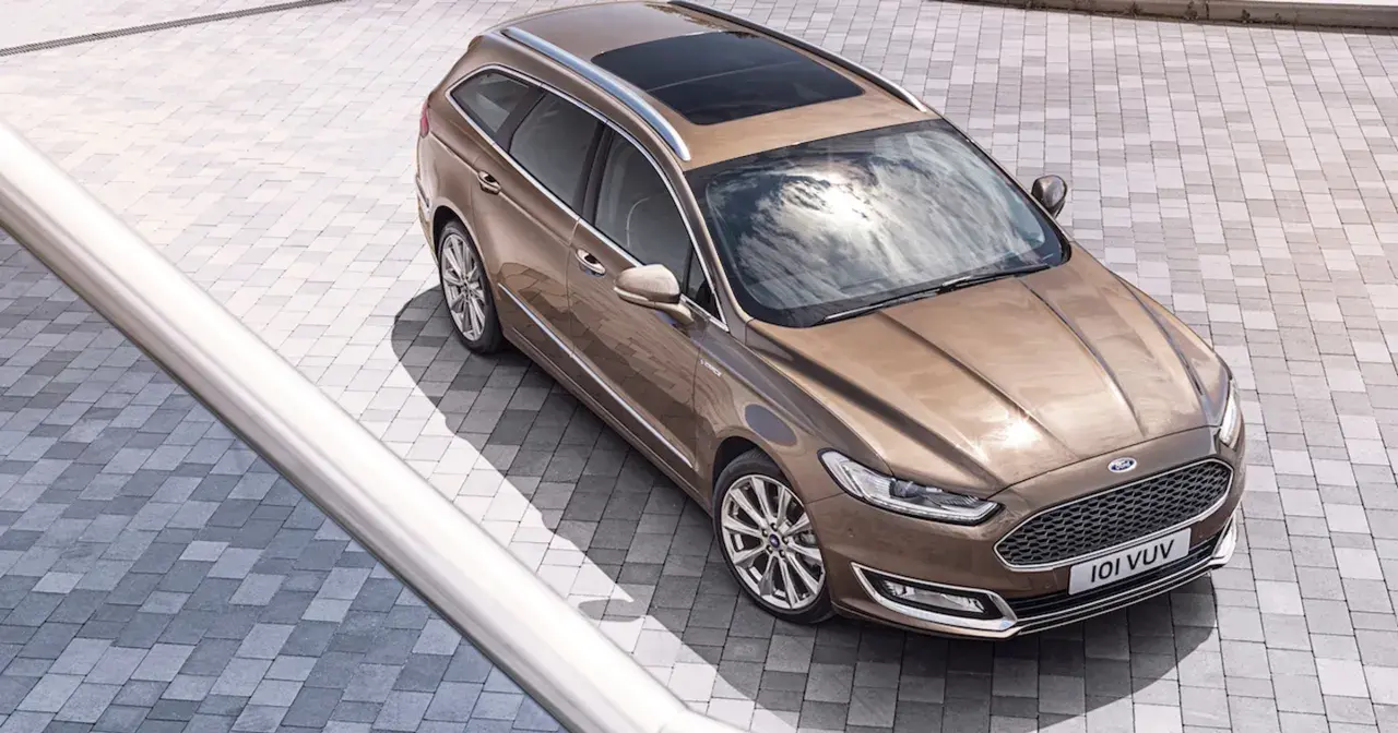 Elegancki, brązowy Ford Vignale kombi z panoramicznym dachem, lśniącym na tle nowoczesnej kostki brukowej.