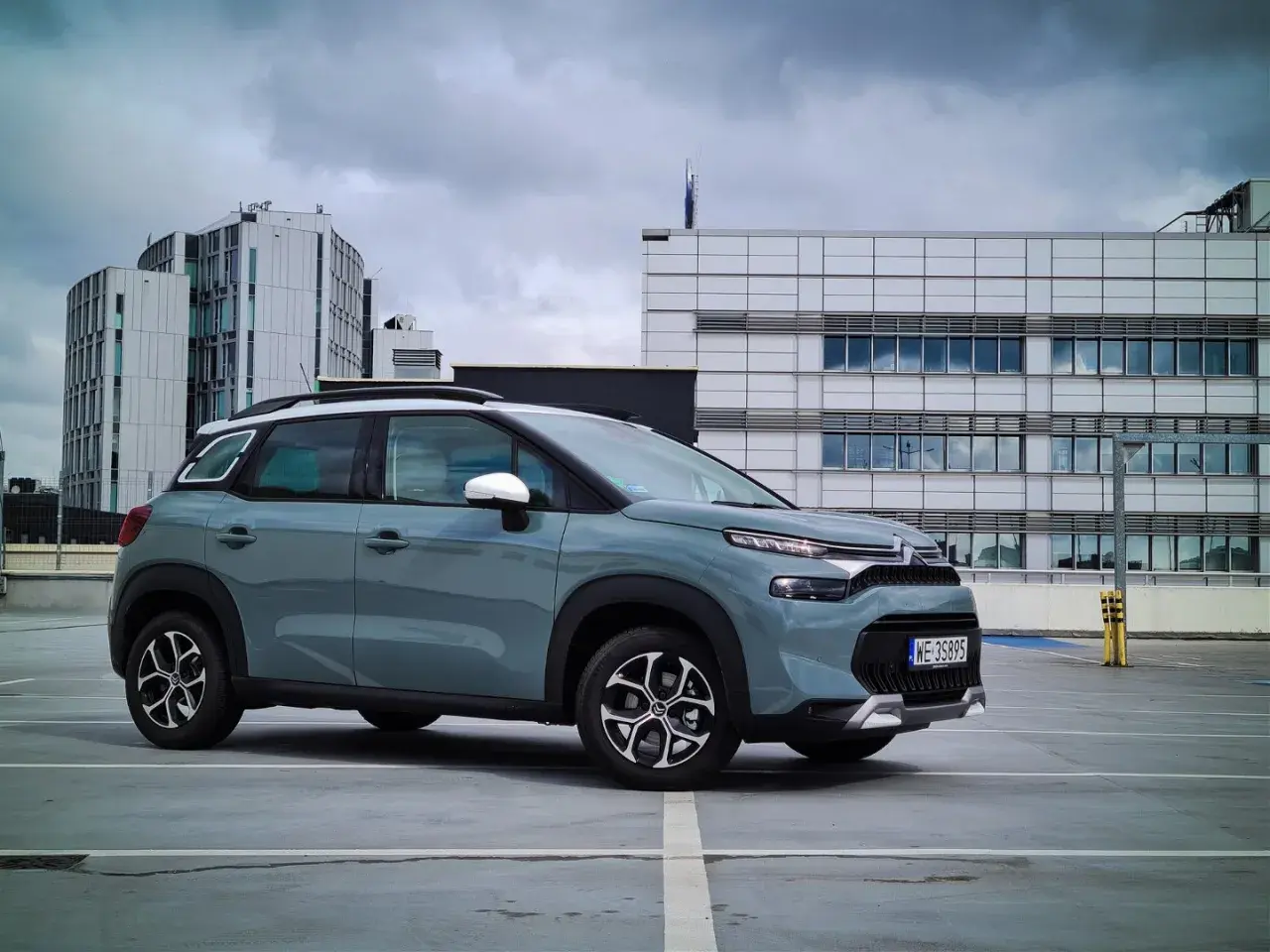 Szary Citroen C3 na parkingu przed nowoczesnymi budynkami. Wiele osób szuka **citroen c3 opinie** przed zakupem.