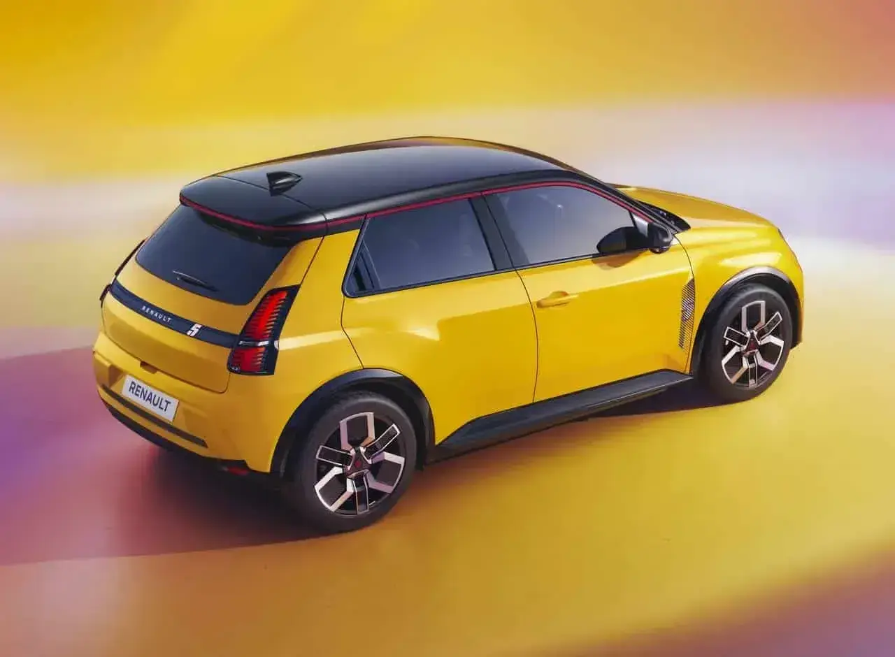 Nowe Renault 5 w jaskrawym żółtym kolorze z czarnym dachem i czerwonymi akcentami, prezentuje nowoczesny design.