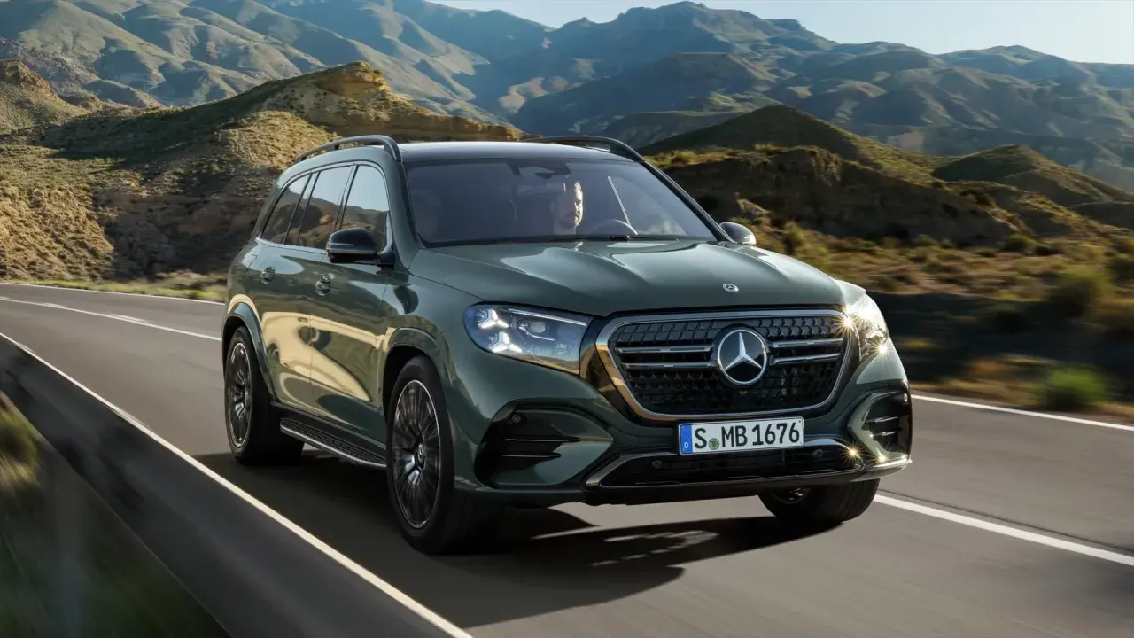 Zielony Mercedes-Benz GLS przemierza malowniczą, górską drogę.