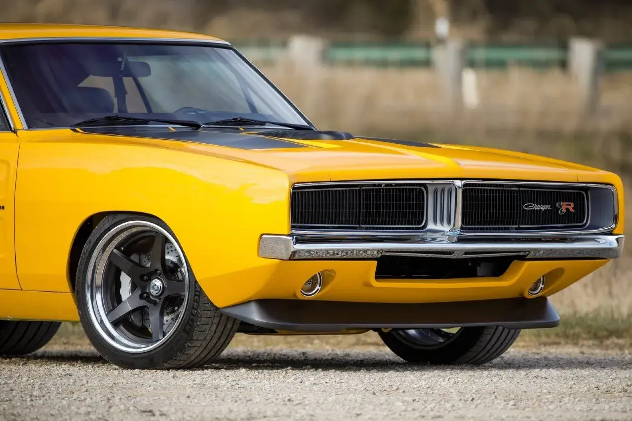 Żółty Dodge Charger 1970 z czarnymi pasami na masce i chromowanym grillem.