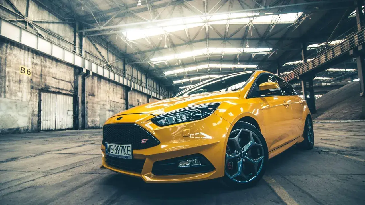 Żółty Ford Focus ST 2010 w hangarze, gotowy do akcji.