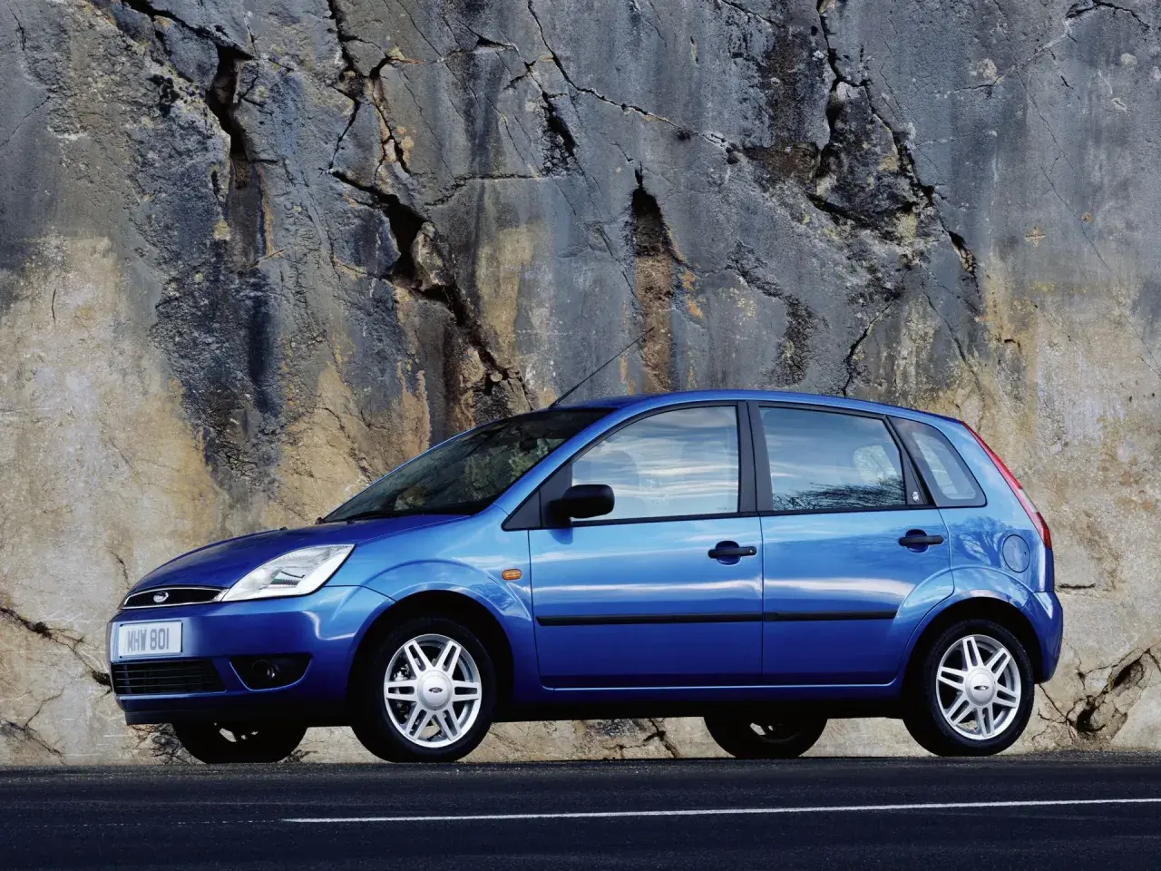 Niebieski Ford Fiesta Mk5 zaparkowany przy skalnej ścianie.