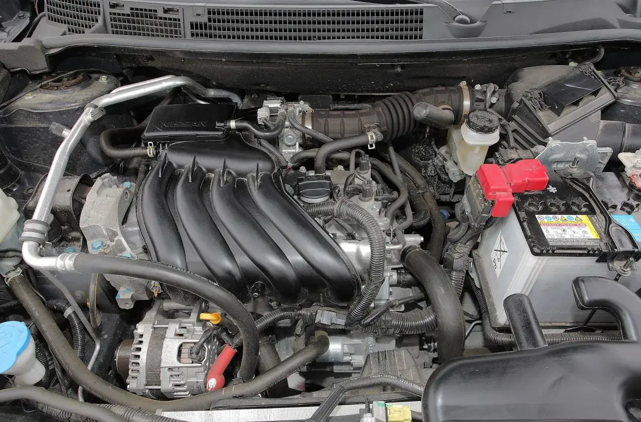 Silnik Nissan Qashqai J10, z widocznym kolektorem dolotowym, akumulatorem i innymi elementami.