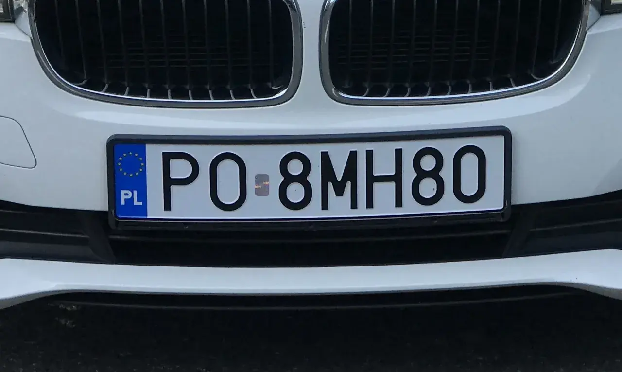 Białe auto z tablicą rejestracyjną PO 8MH80.