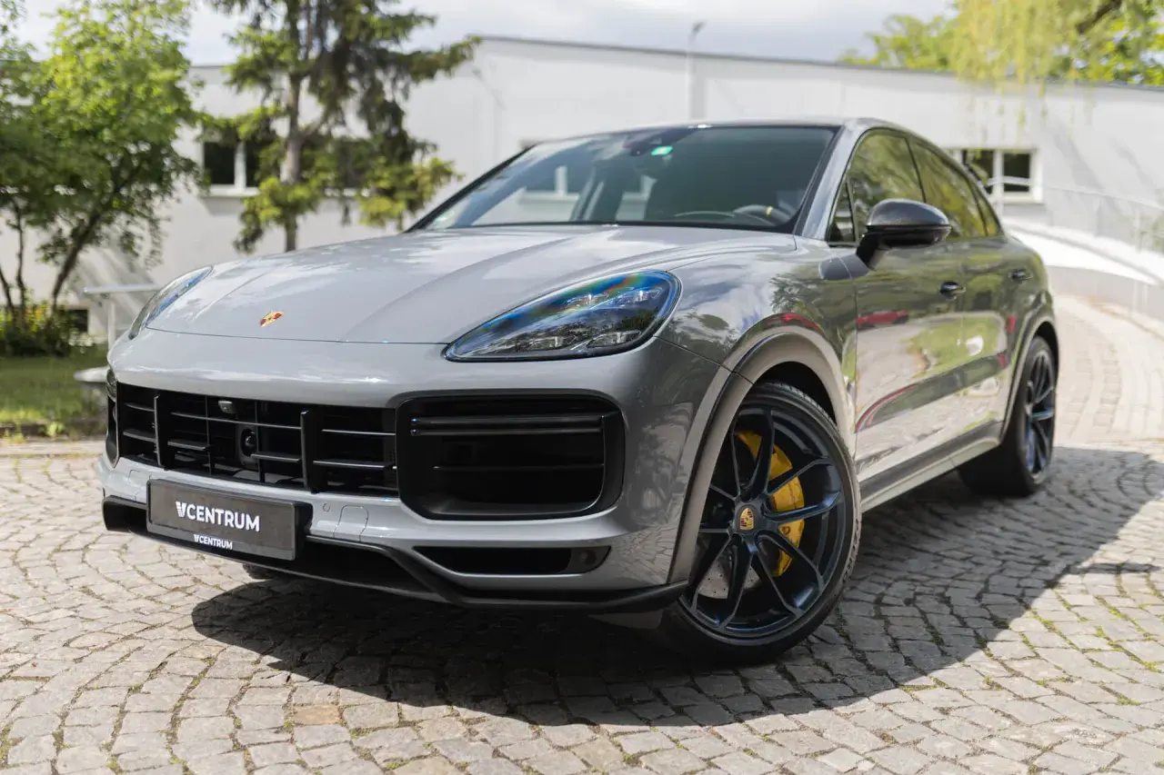 Szary Porsche Cayenne Turbo GT z żółtymi zaciskami hamulcowymi stoi na brukowanej nawierzchni.