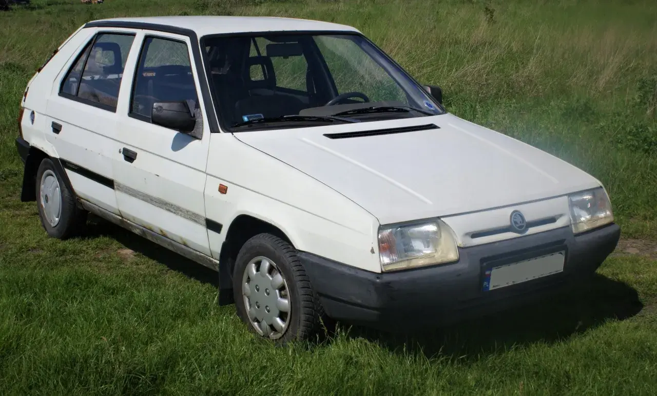 Biały Skoda Favorit stoi na trawie.