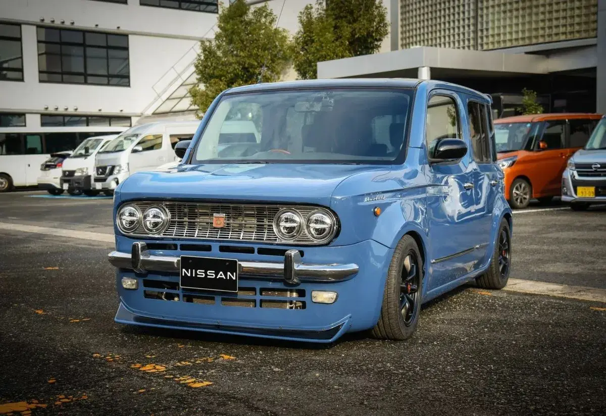 Niebieski Nissan Cube z chromowanymi zderzakami i grillem, obniżonym zawieszeniem i czarnymi felgami.