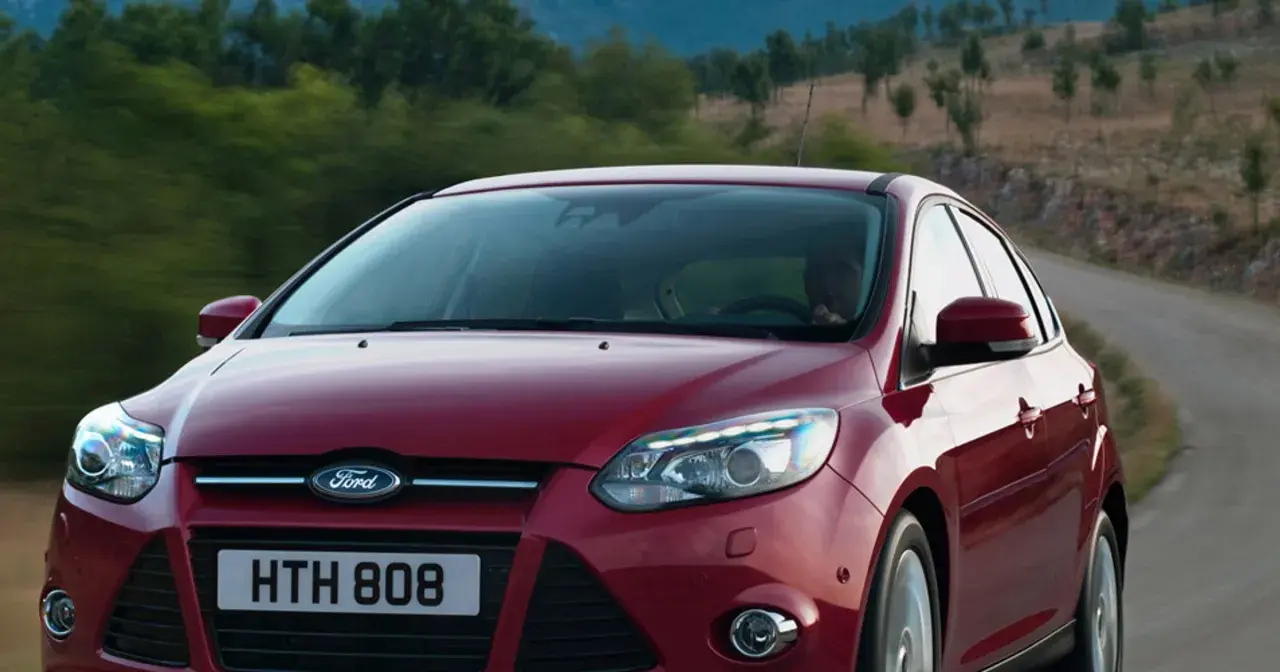 Czerwony Ford Focus 2011 na krętej drodze wśród zieleni.
