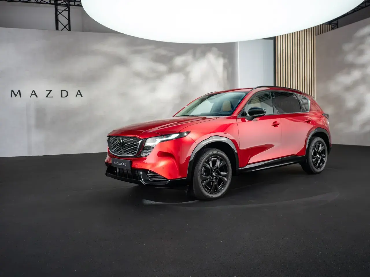 Błyszcząca, czerwona, nowa Mazda CX-5 prezentowana na czarnej scenie.